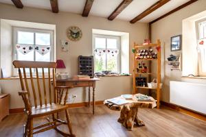 a room with a chair and a table and windows at Chambres d'hôtes, Les Combes in Orbey