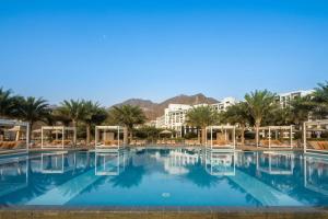 a large swimming pool with palm trees and buildings at InterContinental Fujairah Resort by IHG in Al Aqah