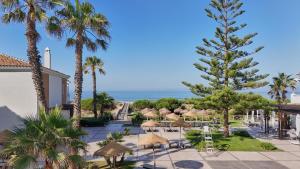 a view of the beach from a resort with palm trees and umbrellas at Barceló Punta Umbría Mar in Punta Umbría