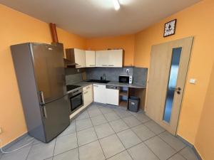 a kitchen with a stainless steel refrigerator and white cabinets at Penzion U Bártů, Dešov in Desov +7 photos