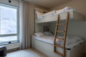 a bunk bed with a ladder in a room with a window at Twintip Apartments in Åre