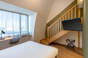a room with a bed and a tv and a staircase at Sure Hotel by Best Western Dijon Sud in Chenôve