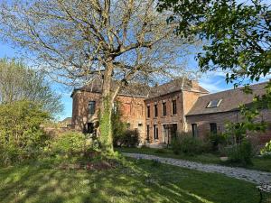 an old brick building with a tree in the yard at La Loge Appartement 1 in Beauquesne