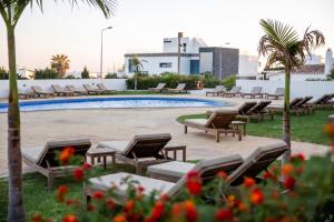 a pool with chaise lounges and chairs next to a resort at Hotel Maritur - Adults Only by Pierre & Vacances in Albufeira