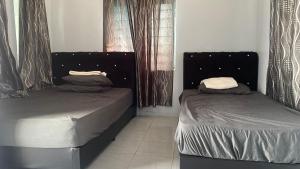two beds sitting in a room with curtains at Hotel O D Longan Cottage in Kampung Tikam Batu