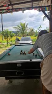 a man playing pool on a pool table at SleepHere Homestay in Bayan