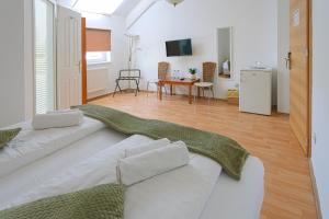 a living room with a white couch and a kitchen at OÁZIS Hotel*** in Nagykanizsa