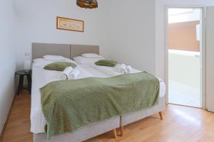 a bedroom with a large white bed with green sheets and towels at OÁZIS Hotel*** in Nagykanizsa