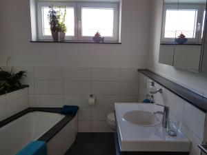 a bathroom with a sink and a tub and a toilet at Double room 75 sqm between Augsburg and Munich in Wiedergeltingen +4 photos