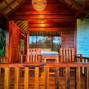 a wooden dining table in a log cabin with a bed at Fuma Bungalow Tetebatu in Tetebatu
