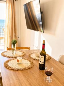 a bottle of wine and a glass on a wooden table at Frente al mar , Piscina ,Playa in El Campello
