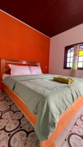 ein Schlafzimmer mit einem großen Bett mit einer orangefarbenen Wand in der Unterkunft Skipper House in Ruteng