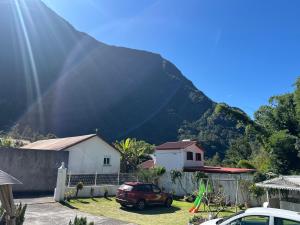 a house with a car parked in front of a mountain at Chez Ava in Salazie