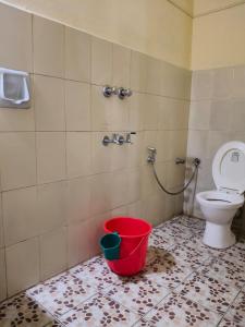 a bathroom with a toilet and a red bucket at Bluemoon Hotel in Cochin +35 photos