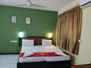 a bedroom with a large bed with green walls at Bluemoon Hotel in Cochin