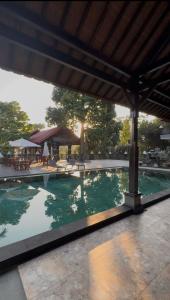 a swimming pool with a pavilion in the background at Casa De Brillo Tegallalang in Tegalalang