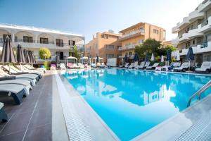 a large swimming pool with lounge chairs and umbrellas at Sunny Days Hotel in Ixia