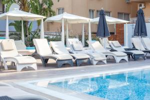 a group of chairs and umbrellas next to a swimming pool at Sunny Days Hotel in Ixia +107 photos
