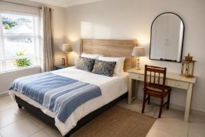 a bedroom with a bed and a desk and a mirror at Die Koraalbos in Stilbaai-Oos