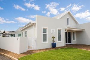 a white house with a white fence at Die Koraalbos in Stilbaai-Oos