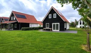 a black and white house with a red roof at Villapark Wulpdal | Villa De Wulp in Scherpenisse