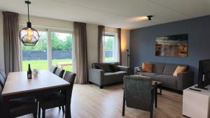 a living room with a table and chairs and a couch at Villapark Wulpdal | Villa De Wulp in Scherpenisse
