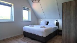 a bedroom with a bed with two towels on it at Villapark Wulpdal | Villa De Wulp in Scherpenisse