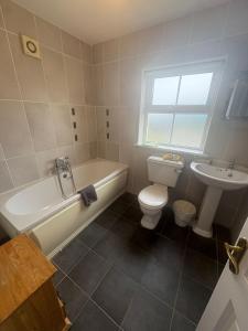 a bathroom with a tub and a toilet and a sink at The Cloverhill House in Mullaghbane