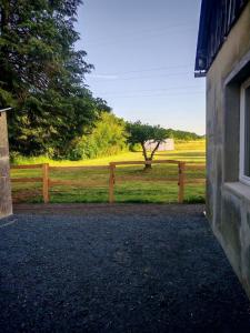 a wooden fence with a tree in a field at Studio indépendant tout équipé proche circuit des 24 Heures in Teloché