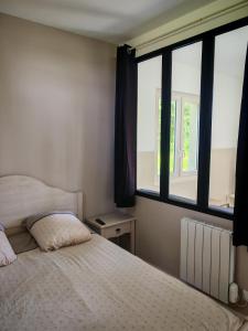 a bedroom with a bed and a large window at Studio indépendant tout équipé proche circuit des 24 Heures in Teloché