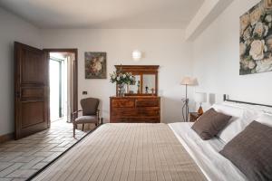 a bedroom with a bed and a dresser and a chair at Oasi Orange Villa with Jacuzzi in Paterno
