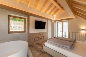a bedroom with a tub and a tv on a wall at Casera Malvan, private wellness chalet in Belluno