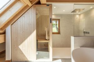 an attic bathroom with a glass door leading to a tub at Casera Malvan, private wellness chalet in Belluno