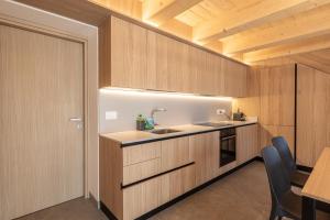 a kitchen with wooden cabinets and a sink at Casera Malvan, private wellness chalet in Belluno
