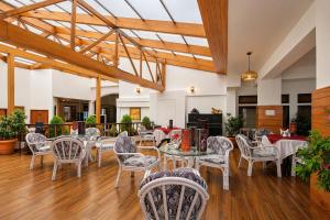 a restaurant with white tables and chairs and wooden ceilings at Central Heritage Resort & Spa Formerly Fortune ITC Resort in Darjeeling