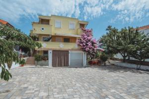 a large yellow house with a driveway at Apartmani Saric A&K in Vir