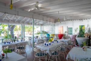 a restaurant with white tables and chairs and windows at Oualie Beach Resort in Nevis