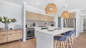 a kitchen with white counter tops and blue stools at Kokoon in Pokolbin +13 photos