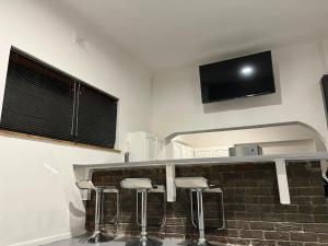 a bar with stools and a television on a wall at Blue Moon Guest Rooms in Bellville