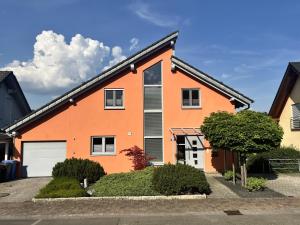 an orange house with a white garage at Ferienwohnung Haus Hahnfelsblick in Erfweiler