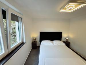 a bedroom with a white bed and two windows at Sunrise Villa Lopar in Lopar