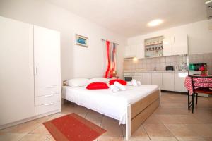 a bedroom with a bed with red pillows and a kitchen at Old Town Accommodation in Bol