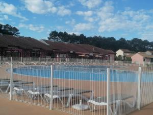 a fence with tables and chairs in front of a pool at Le petit paradis in Soustons