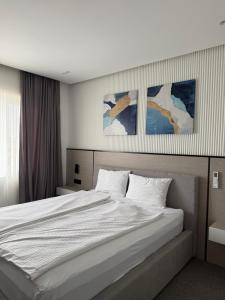 a bedroom with a large white bed with paintings on the wall at Sliv in Vinica