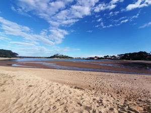 a beach with sand and a blue sky and clouds at Le petit paradis in Soustons