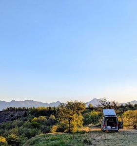 a van parked in a field with mountains in the background at Campagne Vallauris chambres in Sisteron