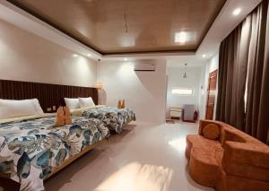 a bedroom with a bed and a chair at Central 1 Suites in Mambajao