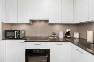 a kitchen with white cabinets and a microwave at AirHosted - Lucerne City Centre in Lucerne