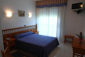 a bedroom with a blue bed and a television at Hotel Jr in Villalonga