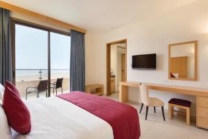 a hotel room with a bed, chair and a tv at Ramada Resort Dead Sea in Sowayma
